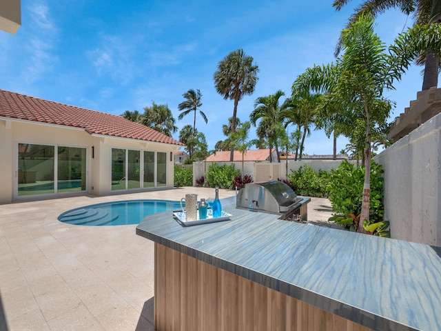 view of swimming pool featuring a grill, an outdoor kitchen, and a patio