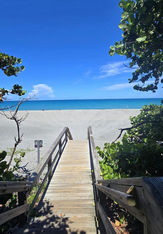 view of dock with a beach view and a water view