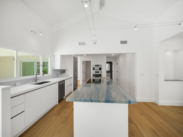 kitchen with high vaulted ceiling, decorative backsplash, white cabinets, and sink