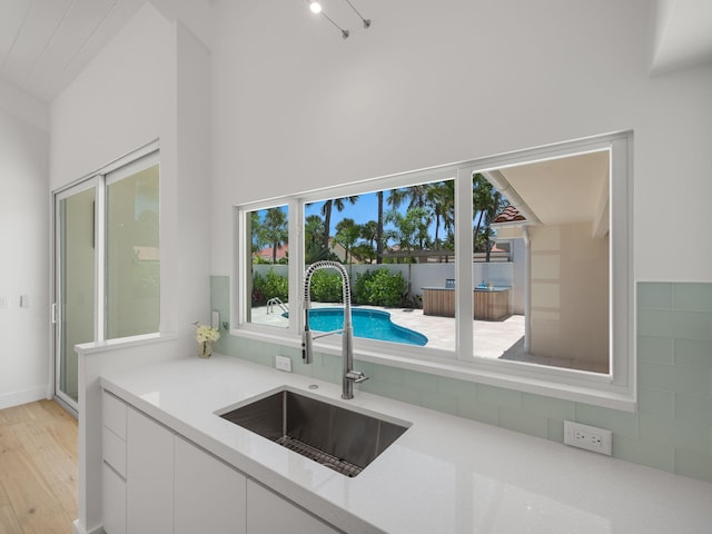 kitchen with a healthy amount of sunlight, white cabinets, and sink