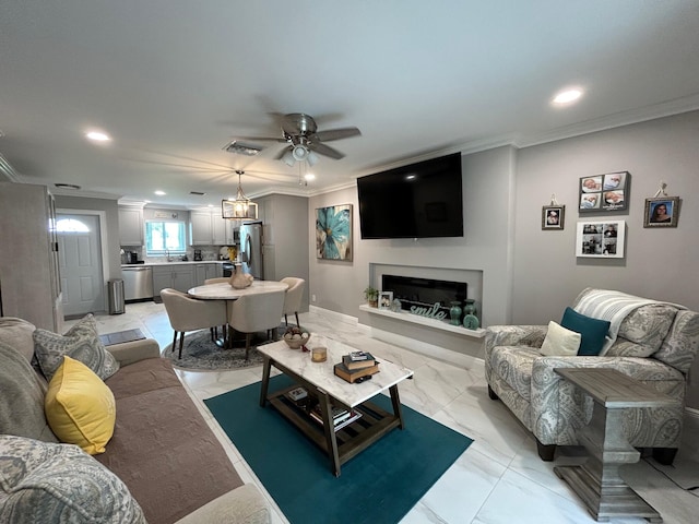 living room with ceiling fan with notable chandelier, crown molding, and sink