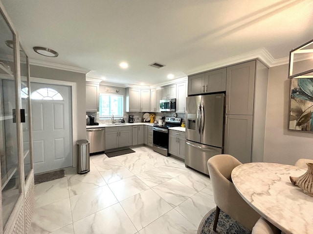 kitchen featuring stainless steel appliances, sink, gray cabinets, decorative backsplash, and ornamental molding