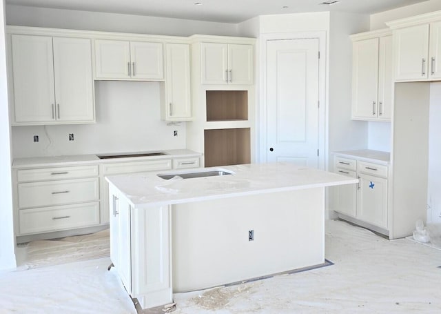 kitchen featuring light stone countertops, a center island, white cabinets, and black electric stovetop