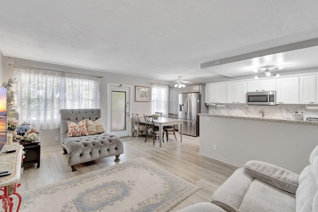 living room featuring light hardwood / wood-style floors and ceiling fan with notable chandelier