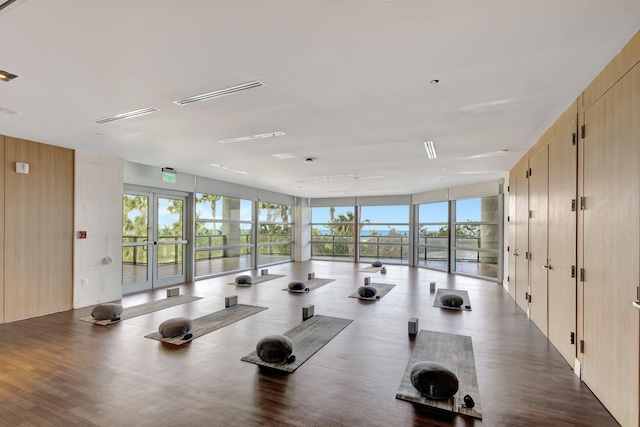 exercise room with floor to ceiling windows, plenty of natural light, french doors, and wooden walls