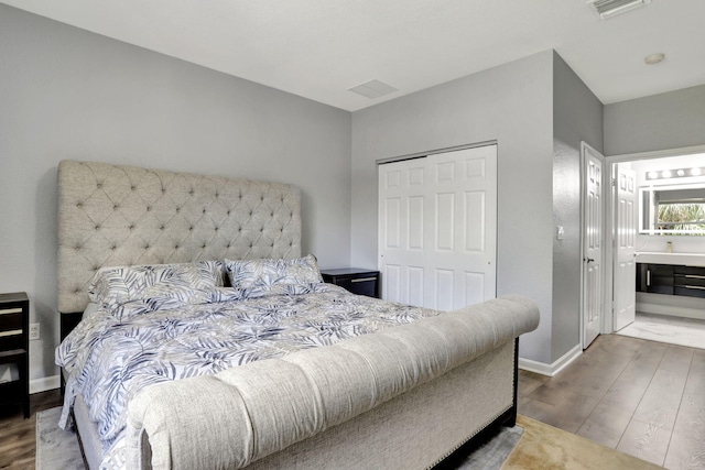 bedroom with connected bathroom, a closet, and hardwood / wood-style floors