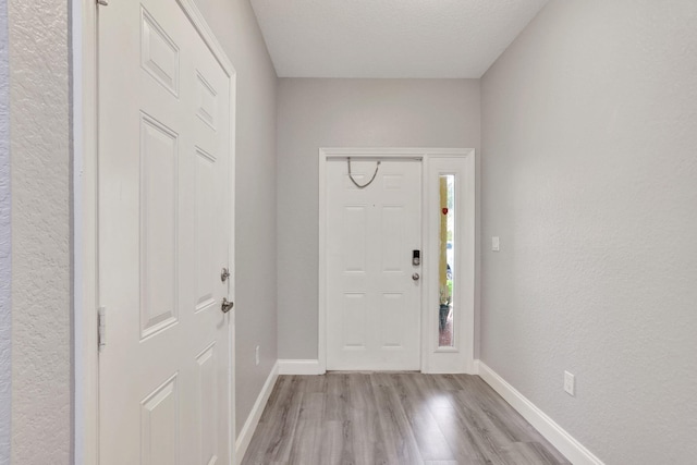 foyer entrance featuring a textured ceiling and light wood-type flooring