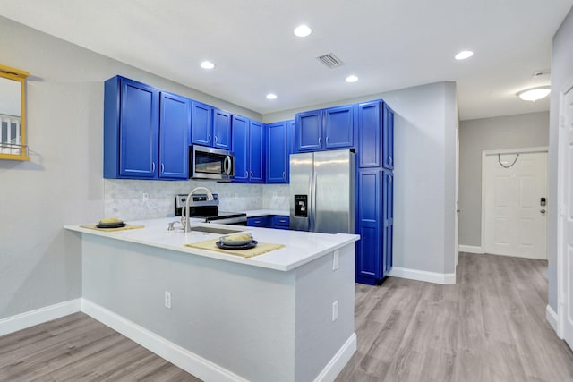 kitchen with backsplash, kitchen peninsula, blue cabinetry, and stainless steel appliances