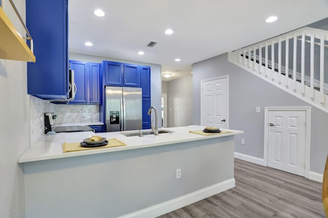 kitchen with blue cabinetry, sink, kitchen peninsula, stainless steel fridge, and stove