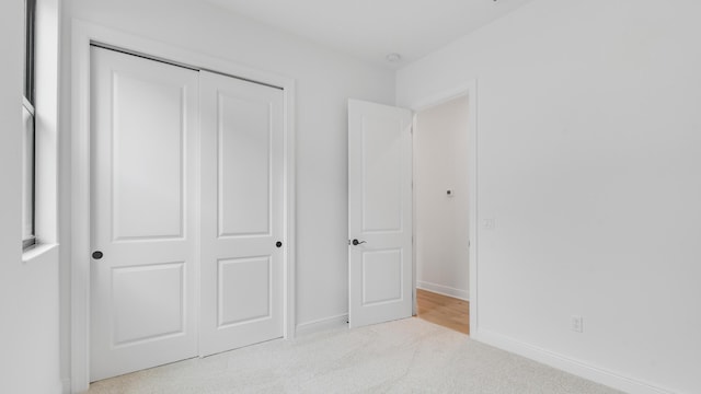 unfurnished bedroom with light colored carpet and a closet