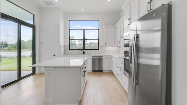 kitchen featuring backsplash, white cabinets, sink, appliances with stainless steel finishes, and a kitchen island