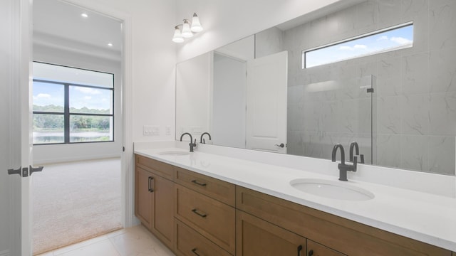 bathroom with a tile shower, tile patterned flooring, vanity, and a healthy amount of sunlight