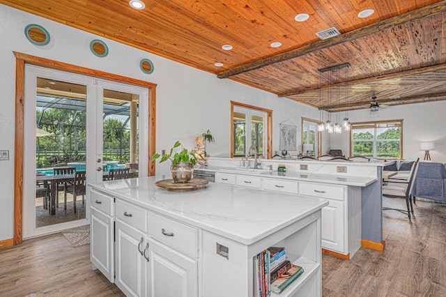 kitchen featuring french doors, wooden ceiling, white cabinets, and a center island