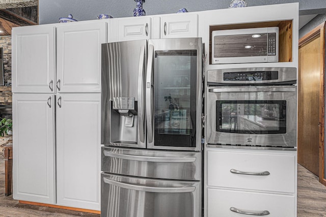 kitchen featuring hardwood / wood-style flooring, white cabinets, and stainless steel appliances