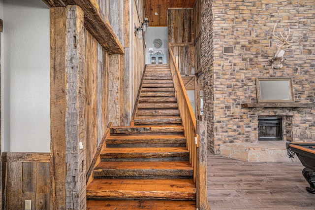 stairway featuring hardwood / wood-style flooring and a stone fireplace