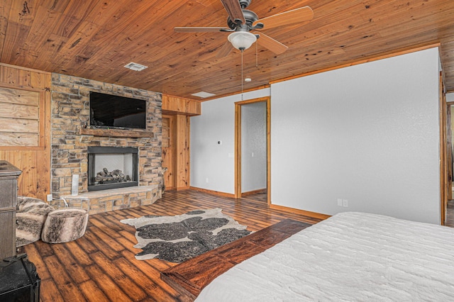 bedroom featuring ceiling fan, a fireplace, wooden walls, hardwood / wood-style flooring, and wood ceiling