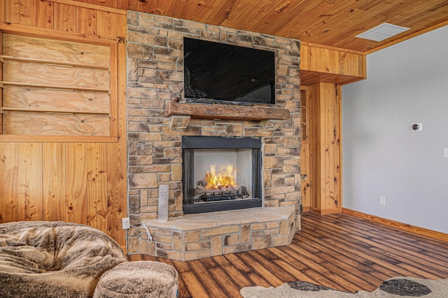 unfurnished living room with wood-type flooring, wood ceiling, wooden walls, and a stone fireplace