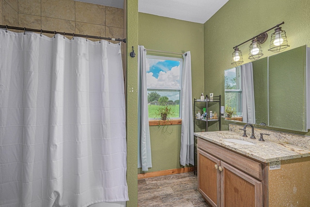 bathroom with hardwood / wood-style flooring, walk in shower, plenty of natural light, and vanity