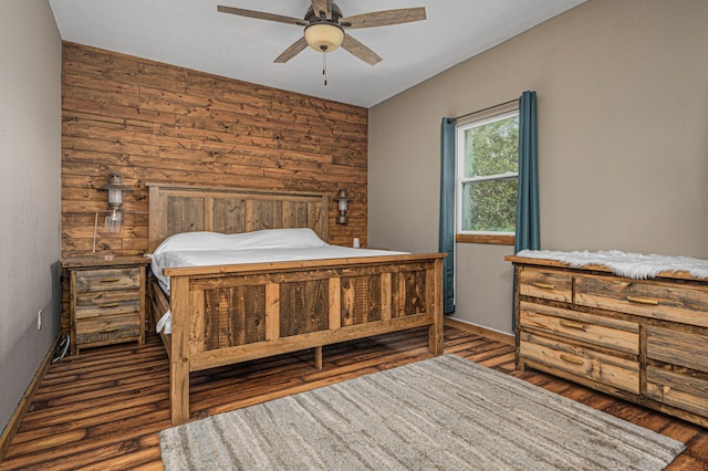 bedroom with ceiling fan, dark hardwood / wood-style floors, and wood walls