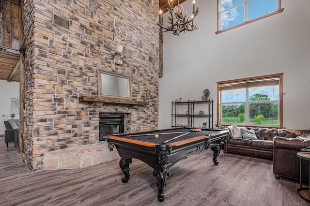 game room featuring hardwood / wood-style flooring, a high ceiling, beamed ceiling, and a fireplace