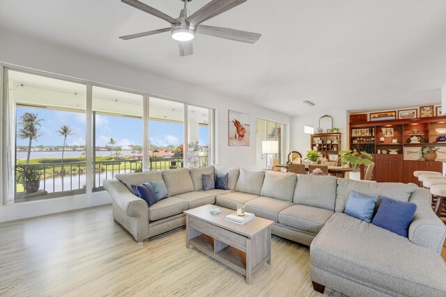 living room featuring ceiling fan, a water view, and light hardwood / wood-style floors