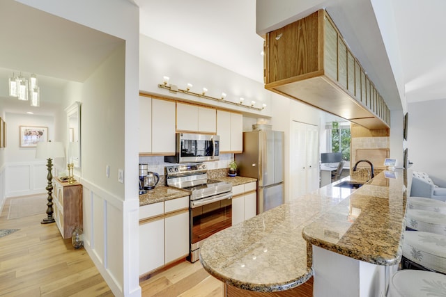 kitchen featuring kitchen peninsula, sink, white cabinets, and stainless steel appliances