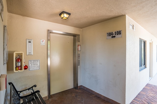 hall featuring elevator and a textured ceiling