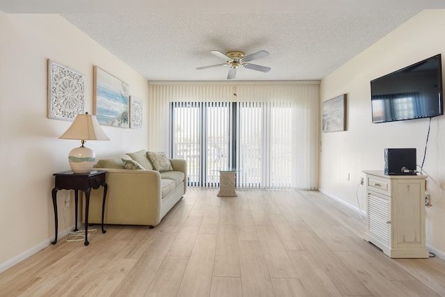 living room with a textured ceiling, ceiling fan, and light hardwood / wood-style floors