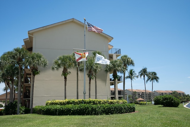 view of home's exterior featuring a balcony and a yard