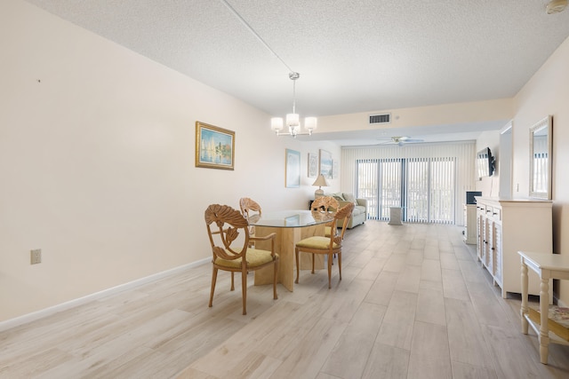 dining room with ceiling fan with notable chandelier, light hardwood / wood-style flooring, and a textured ceiling