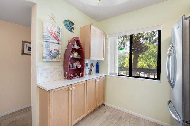 interior space with plenty of natural light, light hardwood / wood-style floors, light brown cabinetry, and stainless steel fridge