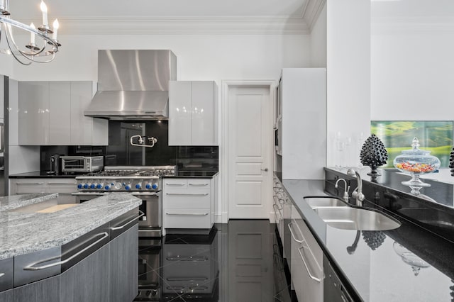 kitchen with sink, wall chimney range hood, high end stainless steel range oven, dark stone counters, and white cabinets