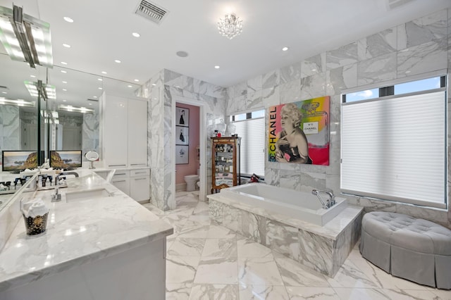 bathroom with vanity, tiled bath, and toilet