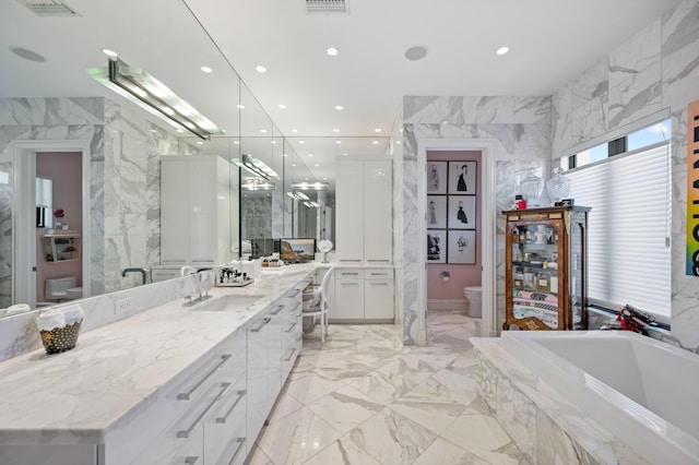 bathroom with vanity, tiled bath, and toilet