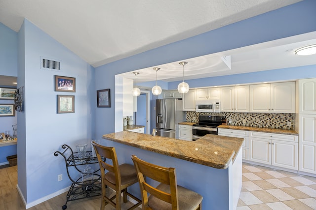 kitchen featuring kitchen peninsula, appliances with stainless steel finishes, tasteful backsplash, stone counters, and hanging light fixtures