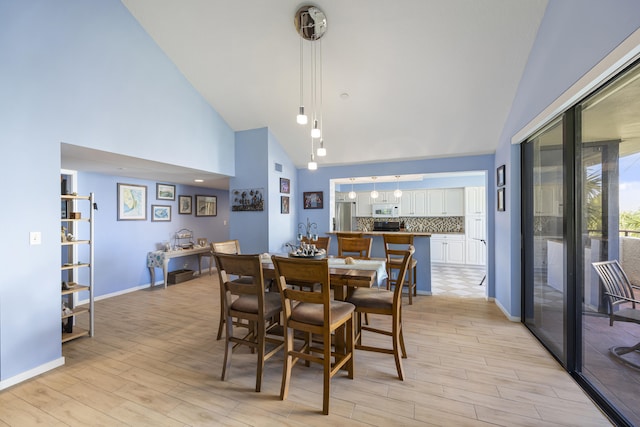 dining space featuring high vaulted ceiling and light hardwood / wood-style floors