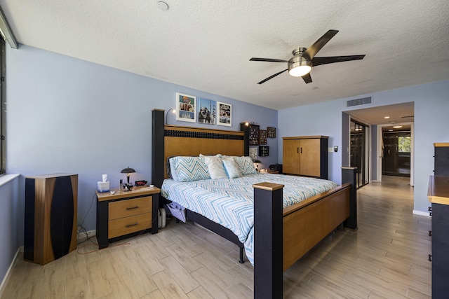 bedroom featuring a textured ceiling, light wood-type flooring, and ceiling fan