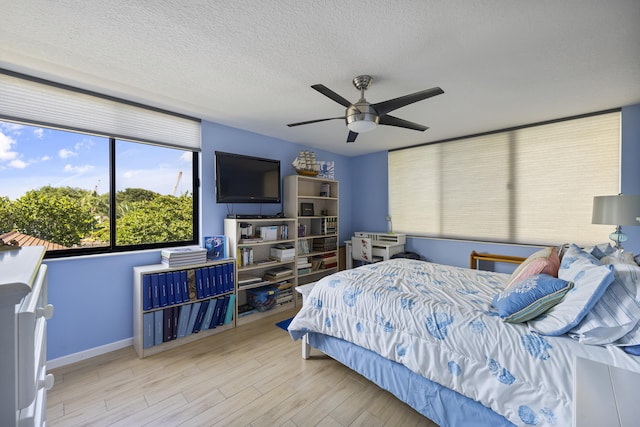 bedroom featuring ceiling fan, a textured ceiling, and light hardwood / wood-style flooring