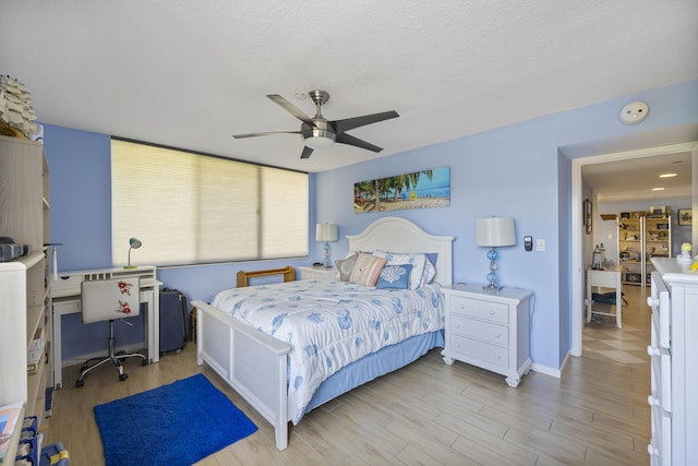 bedroom with ceiling fan, light hardwood / wood-style flooring, and a textured ceiling