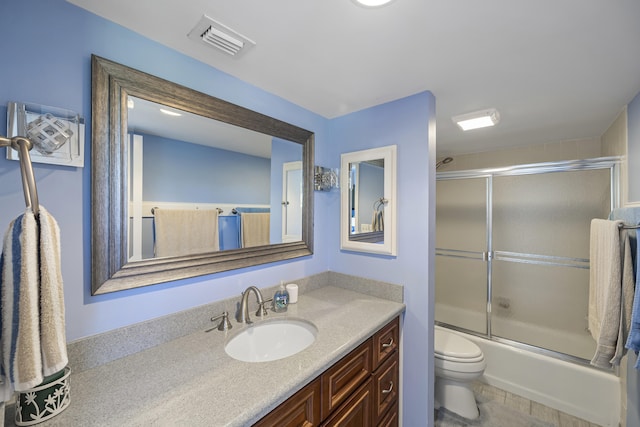 full bathroom featuring toilet, combined bath / shower with glass door, and vanity