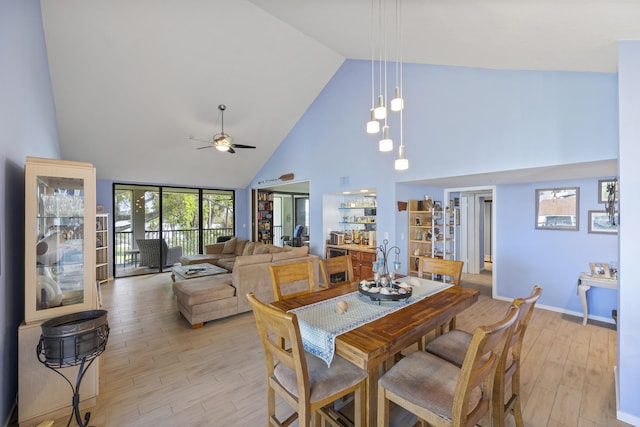 dining room with ceiling fan, high vaulted ceiling, and light hardwood / wood-style floors