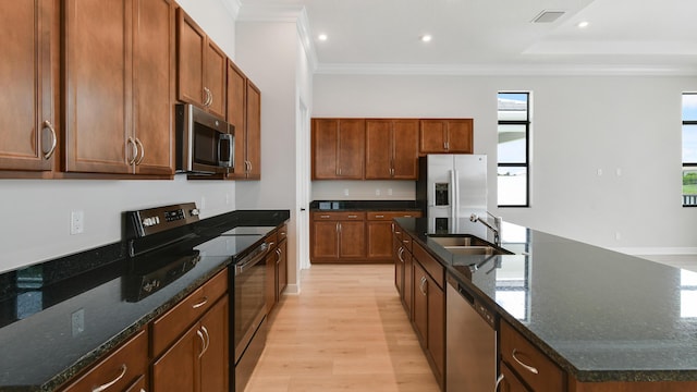 kitchen featuring sink, stainless steel appliances, crown molding, a center island with sink, and light wood-type flooring