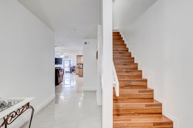 stairway featuring light tile patterned flooring and ceiling fan