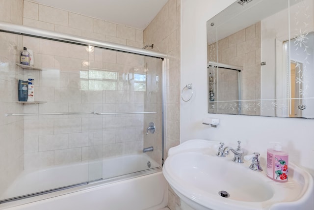 bathroom with sink and bath / shower combo with glass door