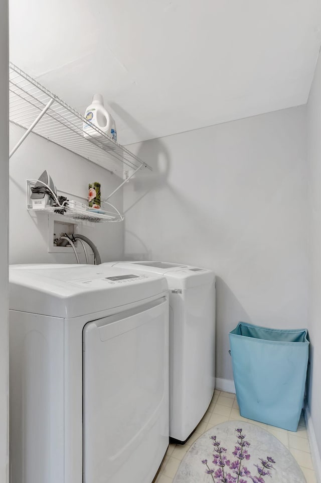 clothes washing area with washer and dryer and light tile patterned floors