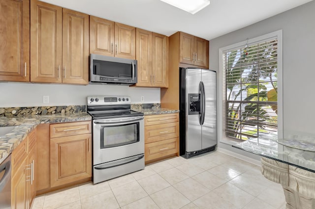 kitchen with appliances with stainless steel finishes, light stone countertops, and light tile patterned floors