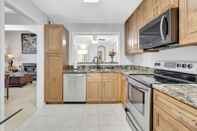 kitchen featuring stainless steel appliances, stone counters, sink, and ceiling fan