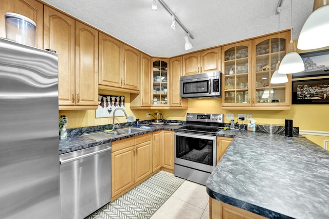 kitchen featuring pendant lighting, stainless steel appliances, sink, rail lighting, and light tile patterned floors