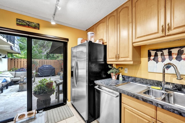 kitchen with a textured ceiling, appliances with stainless steel finishes, rail lighting, sink, and light tile patterned flooring