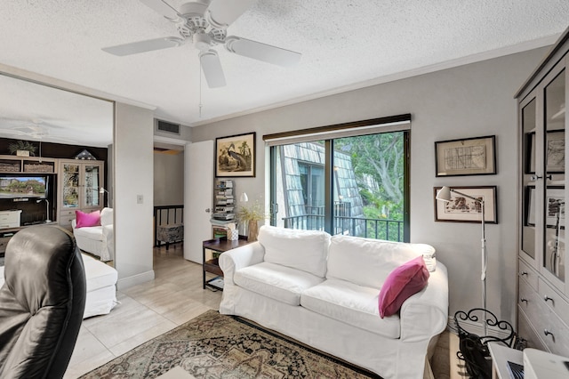 tiled living room with a textured ceiling, ceiling fan, and crown molding